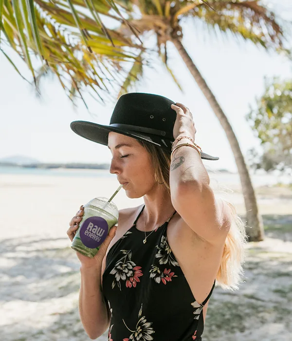Girl holding her hat and drinking a smoothie