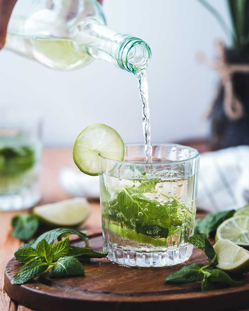 pouring water into a glass with lime and mint